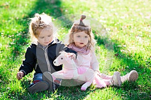 Cute boy and girl sit on grass on summer field. Children in beautiful spring green field.