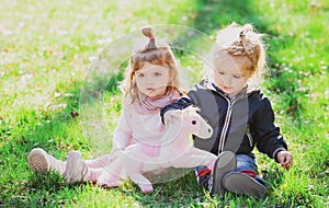 Cute boy and girl sit on grass on summer field. Children in beautiful spring green field.