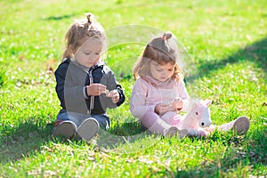 Cute boy and girl on summer field. Cute babys sit on green grass in summertime. Funny little kid on nature. Happy