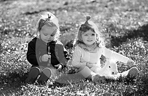 Cute boy and girl on summer field. Happy children playing sitting on green grass in spring park.