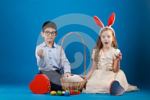 Cute boy and girl with White rabbit in basket with Easter eggs