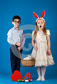 Cute boy and girl with White rabbit in basket with Easter eggs