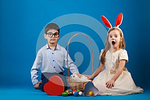 Cute boy and girl with White rabbit in basket with Easter eggs