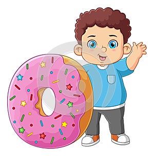 A cute boy good posing and waving with a big pink donut toy
