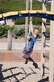 Cute boy hanging on a rope on playground