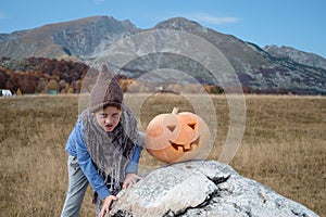 Cute boy in hat and Halloween Carved Pumpkin on the nature background