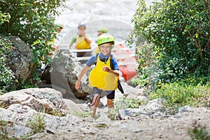 Cute boy in helmet and live vest ready for rafting on the catamaran