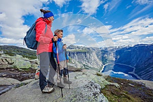 Cute boy and his mother with hiking equipment in the mountains