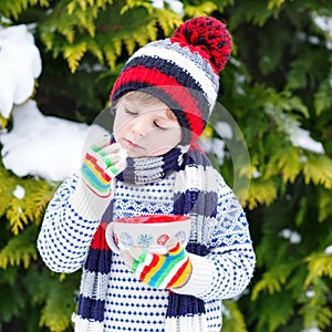 Cute boy holding big cup and hot chocolate drink and marshmallo