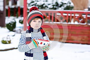 Cute boy holding big cup and hot chocolate drink and marshmallo