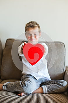 Cute boy holding in hands heart shaped gift box for Valentines day