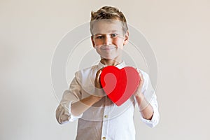 Cute boy holding in hands heart shaped gift box for Valentines day