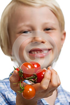 Cute boy holding out bunch of tomatoes