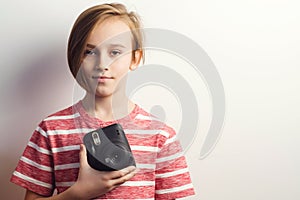 Cute boy holding photo camera. Stylish kid posing over grey background