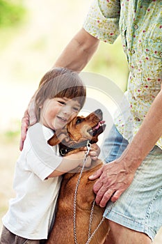 Cute boy hugging a dog at the walk with father