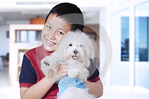 Cute boy hugging maltese dog at home