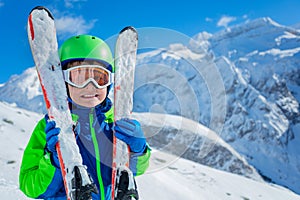 Cute boy hugging ski over mountains portrait