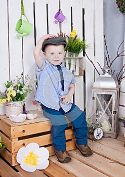 Cute boy in jeans suit and a cap on his headsitting on a bright background juicy