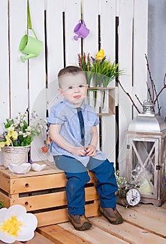 Cute boy in jeans suit sitting on a bright background juicy