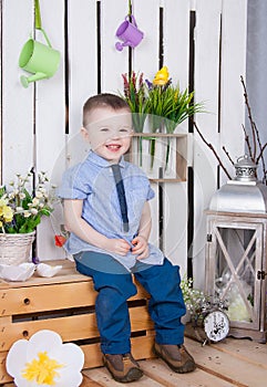 Cute boy in jeans suit sitting on a bright background juicy