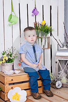 Cute boy in jeans suit sitting on a bright background juicy