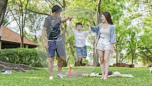 Cute boy jump and hold the hand mother and father in park.Happy family picnic concept