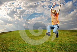 Cute boy jumping on plain meadow