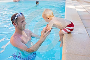 Cute boy, jumping in pool with dad