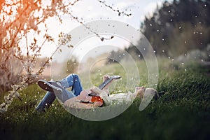 Cute boy lies on the grass with a guitar on sunset