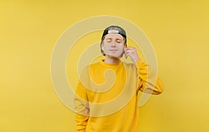 Cute boy listens to music in wireless headphones on a yellow background with closed eyes and smiling