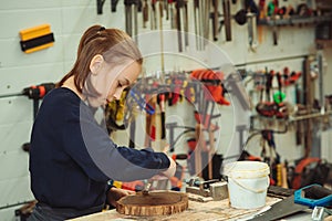 Cute boy makes wooden clock in the workshop. Young carpenter working with wood in craft workshop