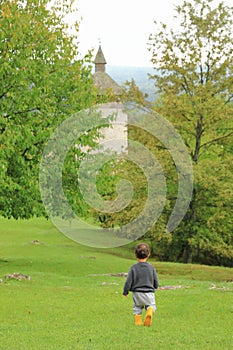 Cute boy on meadow running to old town Dreznik