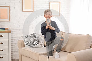 Cute boy with microphone in living room