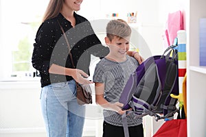 Cute boy with mother choosing backpack