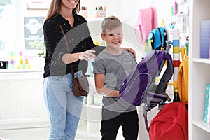 Cute boy with mother choosing backpack