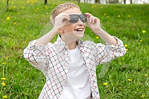 Cute boy with no tooth put on colorblind sunglasses and looks up photo