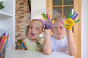 Cute boy with painted hands playing with his little sister at home