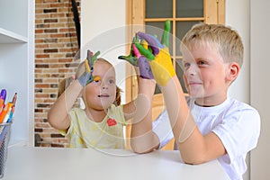 Cute boy with painted hands playing with his little sister at home