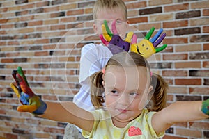 Cute boy with painted hands playing with his little sister at home