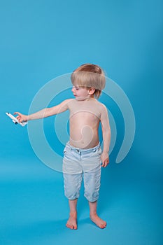 Cute boy play with airplane in hand on blue background