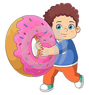 A cute boy playing with a big pink donut toy