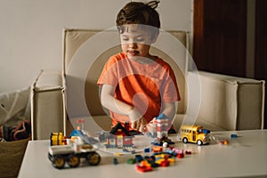 Cute boy is playing constructor at home. Kid playing block toys in home at nursery.