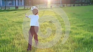 Cute boy playing football with football ball on the sunset in the park. s.