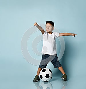 Cute boy playing football, happy child, young male teen goalkeeper enjoying sport game, holding ball