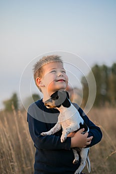 Cute boy playing with his dog in the meadow. Little puppy jack russel terrier on the walk with owner