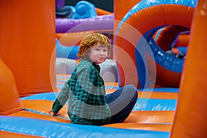 Cute boy playing on inflatable bounce house in entertainment center