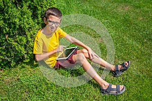 Cute boy playing internet games with tablet on a sunny day