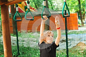 Cute boy playing on monkey bars. Kids sport outdoors. Summer vacation, camp and leisure