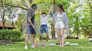 Cute boy playing with mother and father in park.Happy family picnic concept