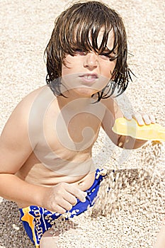 Cute boy, playing with pebbles on the beach in the morning